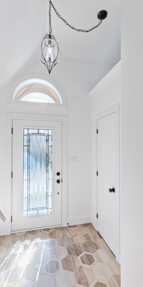 Interior of 446 Woodman custom home entryway with white walls, glass front-door and glass light fixture